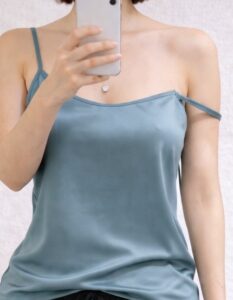キャミソールを着ている女装男子が片の肩紐が落ちている