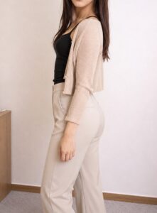 ベージュのパンツ姿で身体を斜めにし片方の腰を後ろへ引いた女装男子の立ち姿