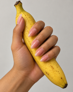 長いピンクのネイルチップを付けた物を持つ様子